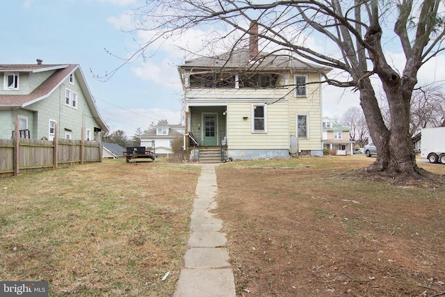 back of property with a chimney, fence, and a yard