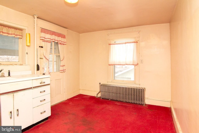 unfurnished bedroom with baseboards, dark carpet, and radiator heating unit