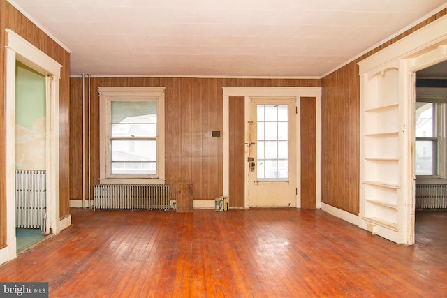 interior space featuring radiator, wooden walls, and hardwood / wood-style floors