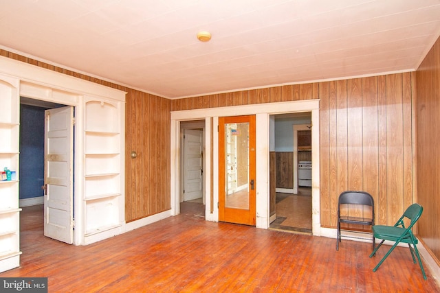 unfurnished room featuring wooden walls, hardwood / wood-style floors, and french doors