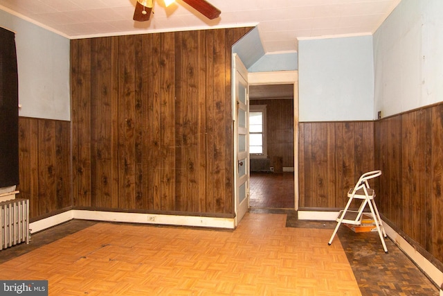 spare room with radiator, wooden walls, and wainscoting