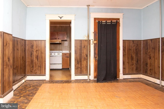 interior space featuring ornamental molding, a wainscoted wall, and wooden walls