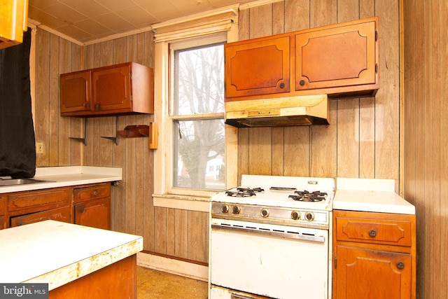 kitchen with wood walls, light countertops, white range with gas cooktop, and under cabinet range hood