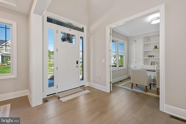 foyer featuring visible vents, wood finished floors, and baseboards