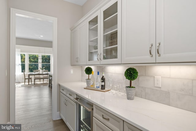 bar featuring beverage cooler, backsplash, and wood finished floors