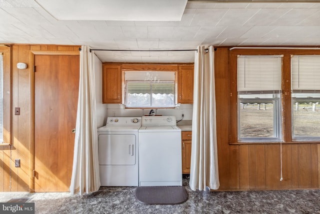 laundry area with cabinet space, wooden walls, and separate washer and dryer