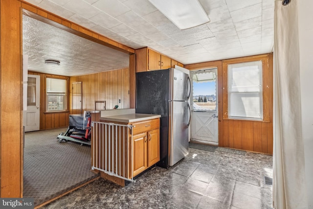 kitchen with wooden walls, visible vents, and freestanding refrigerator