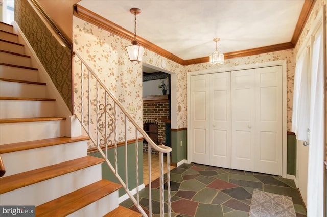 foyer entrance featuring crown molding, stairway, and wallpapered walls