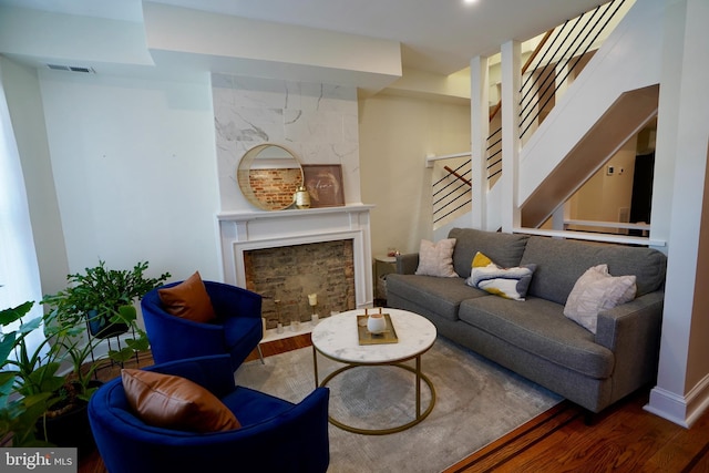 living room featuring stairs, visible vents, a fireplace, and wood finished floors