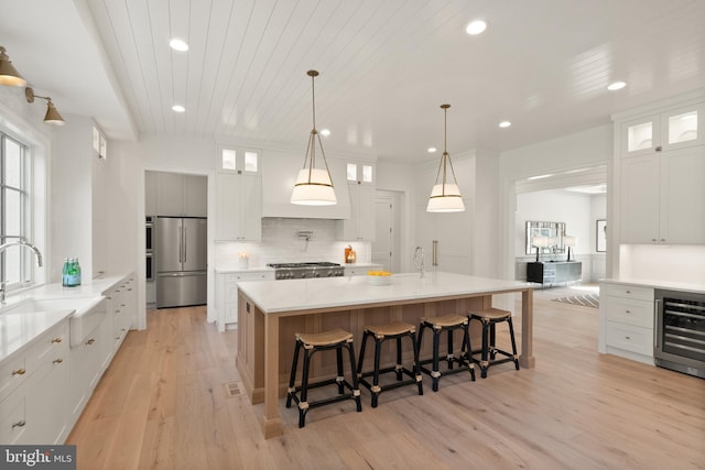 kitchen with range, wine cooler, stainless steel refrigerator, backsplash, and a sink