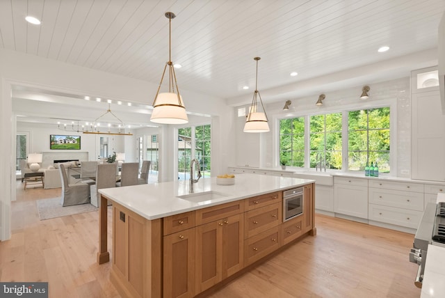 kitchen with a healthy amount of sunlight, light wood-style flooring, a fireplace, and a sink