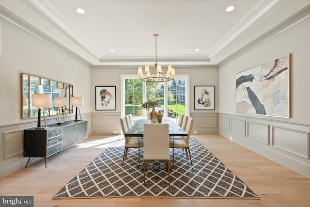 dining space featuring light wood-style flooring, a tray ceiling, and a decorative wall