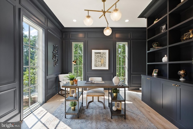 home office featuring built in shelves, crown molding, recessed lighting, a decorative wall, and light wood-style floors