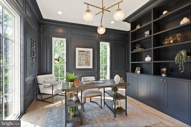 office space featuring ornamental molding, built in features, light wood-style flooring, and a decorative wall