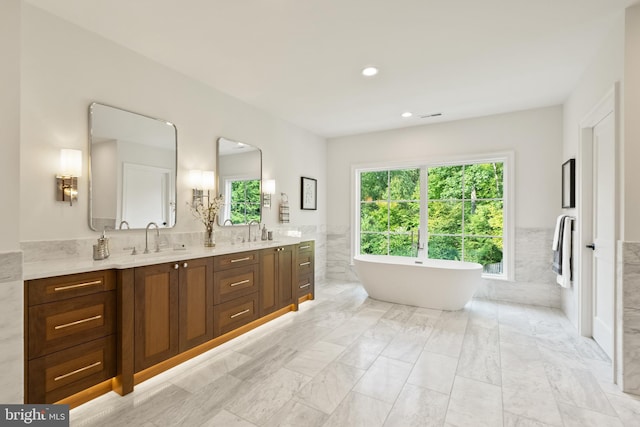 full bath with a sink, tile walls, and a freestanding bath