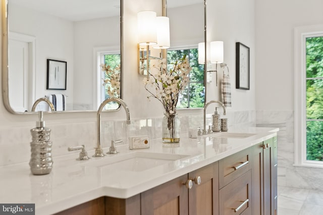 full bathroom with double vanity, a sink, and tile walls