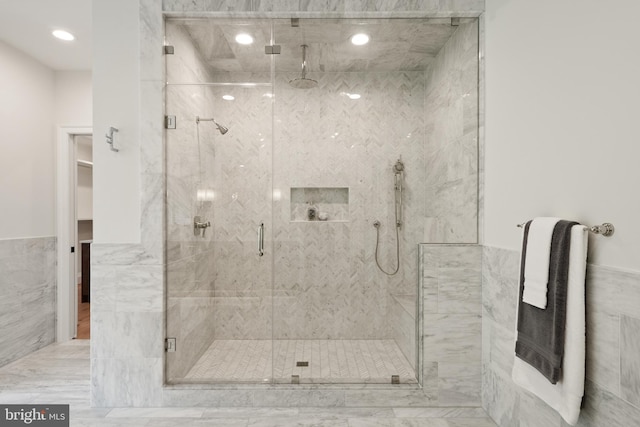 bathroom featuring a wainscoted wall, a marble finish shower, tile walls, and recessed lighting