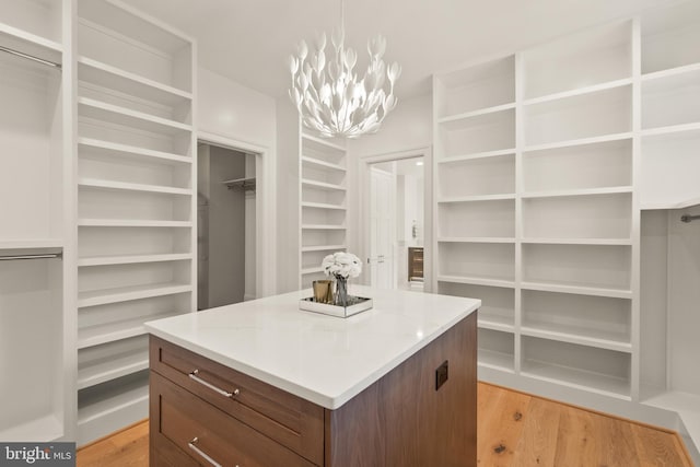 spacious closet featuring light wood-type flooring and a chandelier