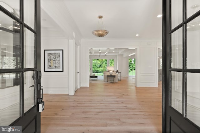 foyer featuring light wood-type flooring, a decorative wall, and crown molding