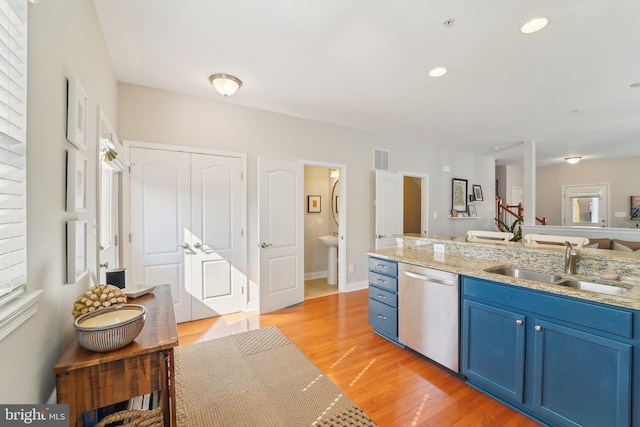 kitchen featuring visible vents, dishwasher, light wood-style flooring, blue cabinets, and a sink