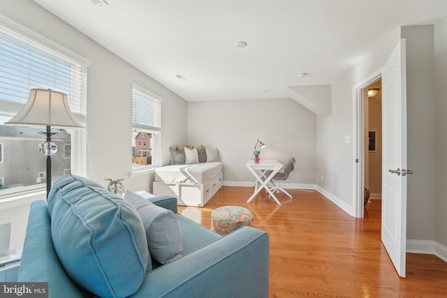 living room featuring visible vents, light wood-style flooring, and baseboards