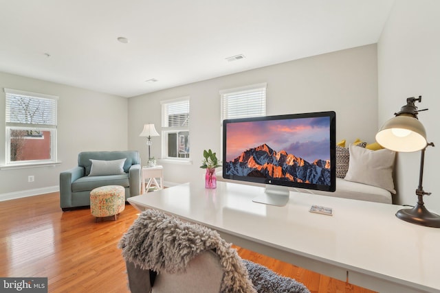 interior space featuring baseboards, plenty of natural light, visible vents, and wood finished floors