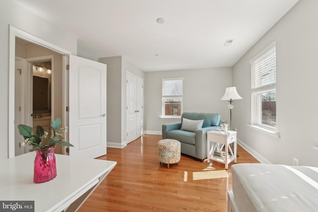 living area with light wood-style floors, visible vents, and baseboards