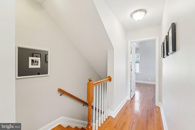 hall with baseboards, light wood finished floors, and an upstairs landing