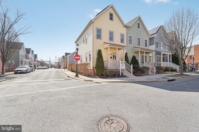 view of road featuring traffic signs, a residential view, curbs, and sidewalks