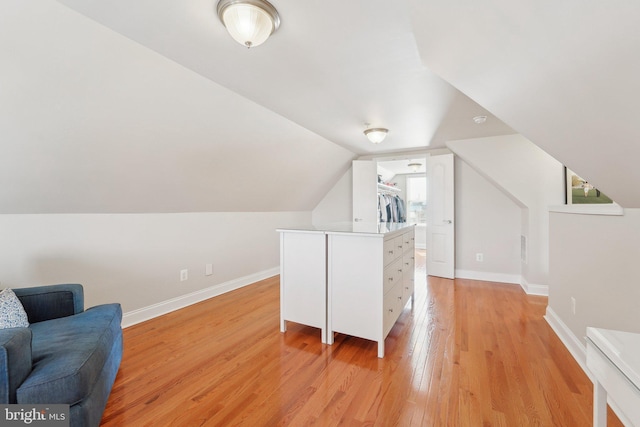 additional living space with lofted ceiling, baseboards, and light wood-style floors