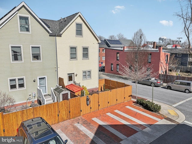 exterior space featuring a fenced front yard, a gate, and roof with shingles