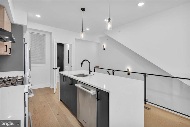 kitchen with stainless steel appliances, a sink, light wood-style floors, light countertops, and modern cabinets