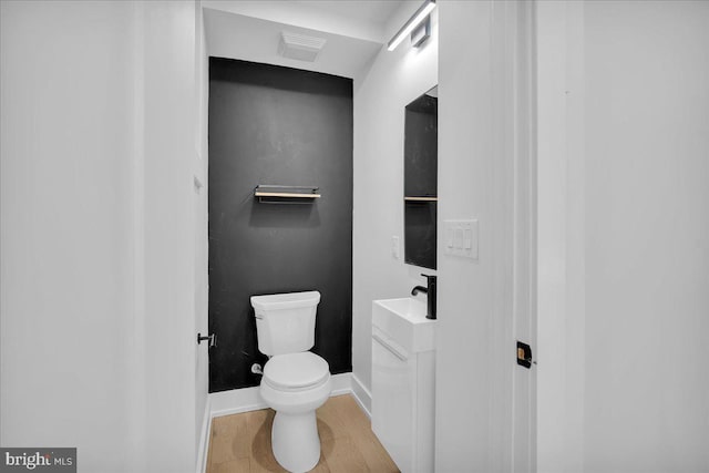 bathroom with visible vents, vanity, toilet, and baseboards