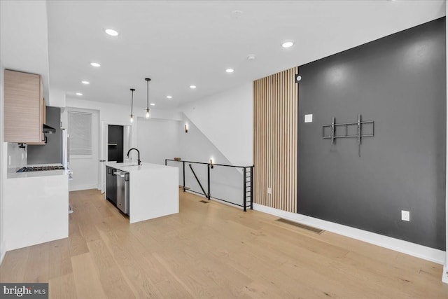 kitchen featuring a center island with sink, visible vents, light wood-style flooring, modern cabinets, and stainless steel dishwasher