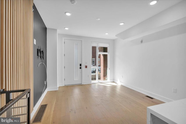 foyer featuring light wood finished floors, visible vents, and baseboards