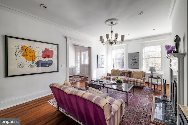 living area featuring baseboards, an inviting chandelier, wood finished floors, and crown molding