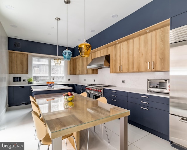 kitchen featuring visible vents, wall chimney range hood, pendant lighting, high quality appliances, and light countertops