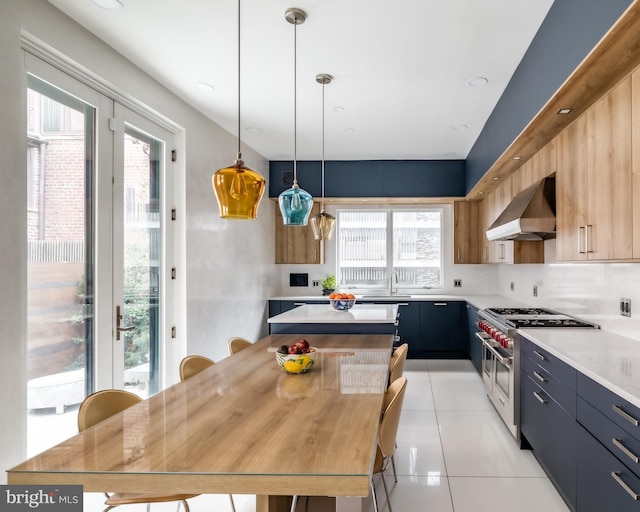 kitchen featuring high end stainless steel range oven, a kitchen island, wall chimney exhaust hood, light countertops, and light tile patterned floors