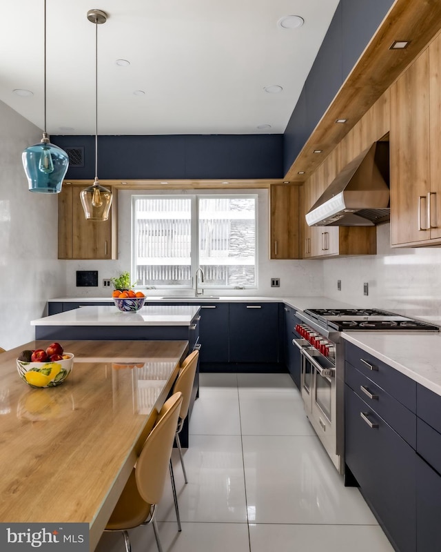 kitchen with wall chimney range hood, double oven range, light countertops, hanging light fixtures, and modern cabinets