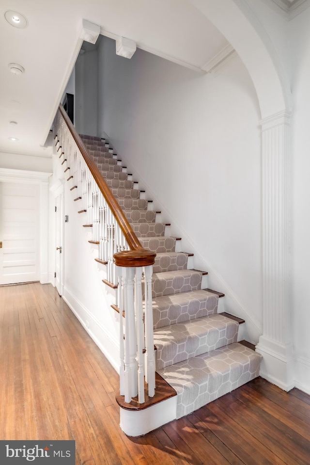 stairs featuring recessed lighting, baseboards, arched walkways, and hardwood / wood-style floors