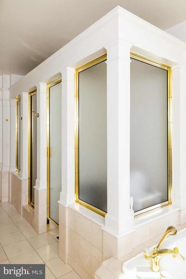 full bath featuring crown molding, a garden tub, a stall shower, tile patterned floors, and ornate columns