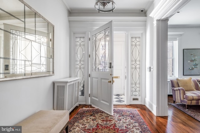 entrance foyer featuring decorative columns, wood finished floors, and crown molding