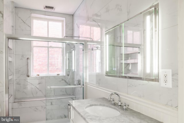 bathroom featuring a marble finish shower, visible vents, and vanity