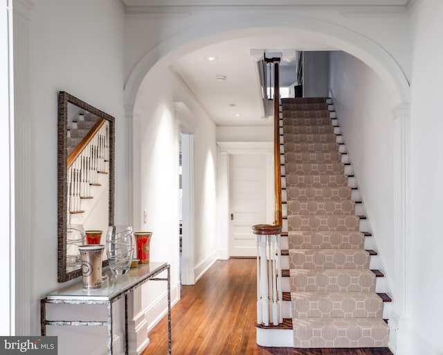 entryway featuring arched walkways, stairway, and wood finished floors