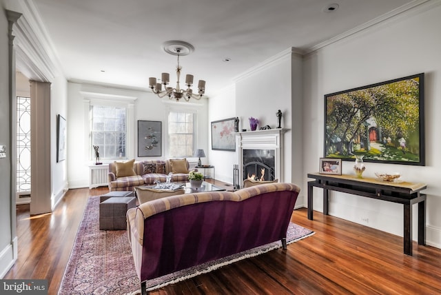 living room with wood finished floors, a high end fireplace, an inviting chandelier, crown molding, and baseboards