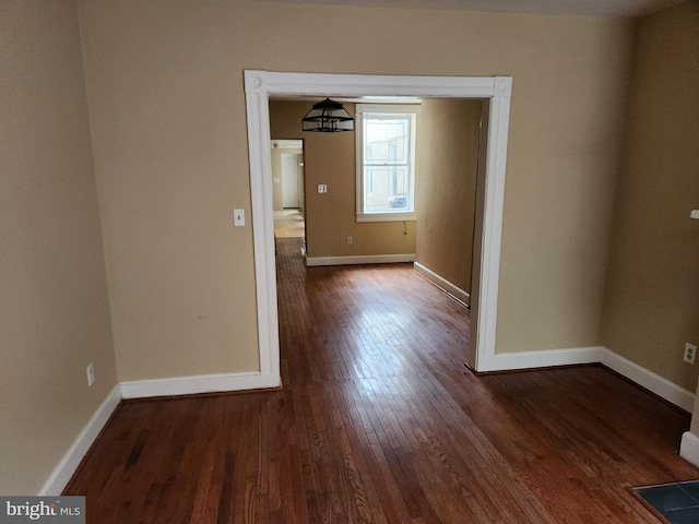 unfurnished room with dark wood-style flooring and baseboards