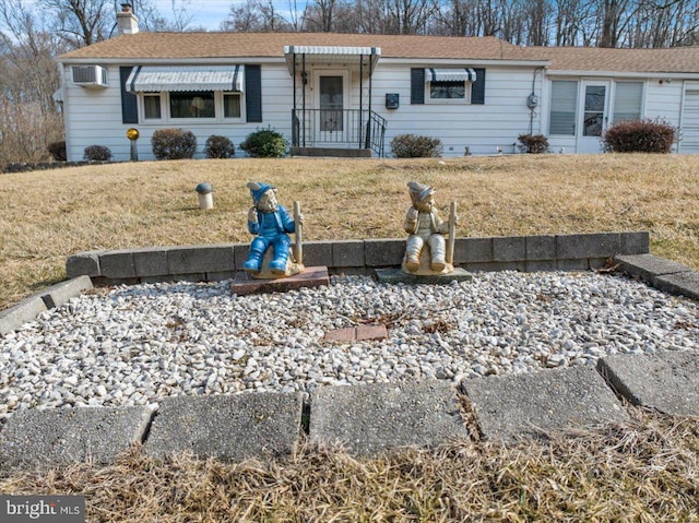 ranch-style home featuring an AC wall unit, a chimney, and a front lawn