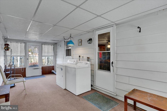 washroom with carpet, laundry area, wood walls, and separate washer and dryer