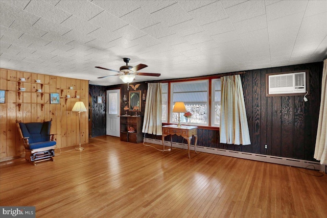 unfurnished room featuring a ceiling fan, a baseboard heating unit, wood finished floors, and a wall mounted air conditioner