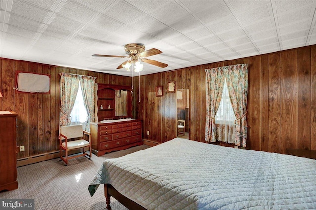 bedroom featuring wood walls, a baseboard radiator, and carpet flooring